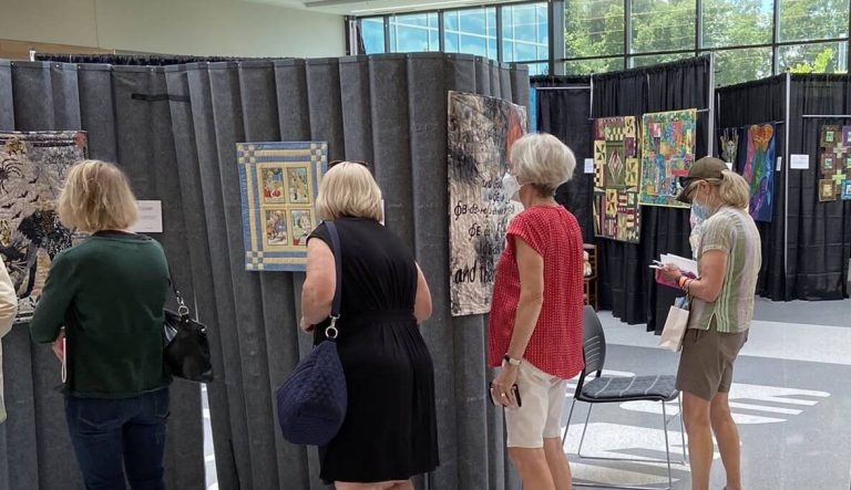 Viewers admiring small quilts at the 2022 GAAQG Quilt Show