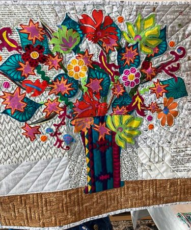 Quilt with vibrant appliqué flowers in a vase