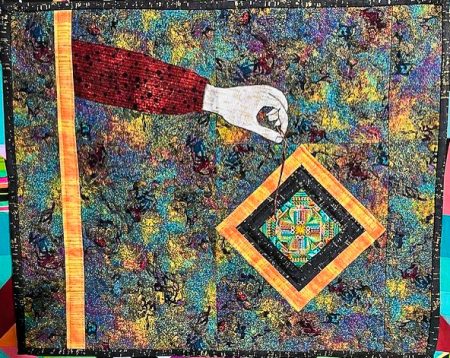 Quilt with hand holding needle and thread working on a complex quilt square