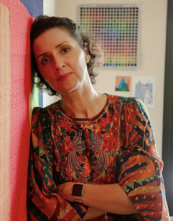 carolina oneto leaning on one of her quilts