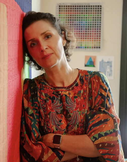 carolina oneto leaning on one of her quilts