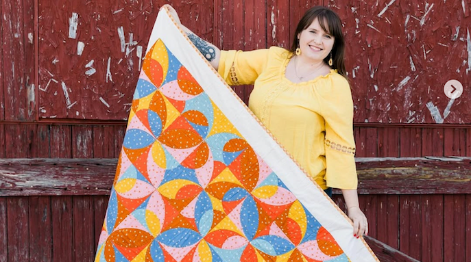 Erin Grogan holding quilt in front of barn