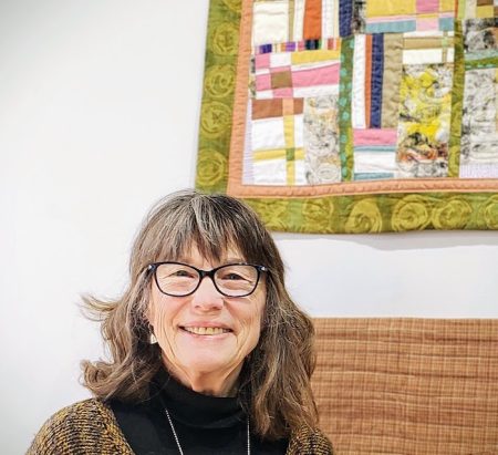 Mary wearing glasses, quilt with lime green border in the background