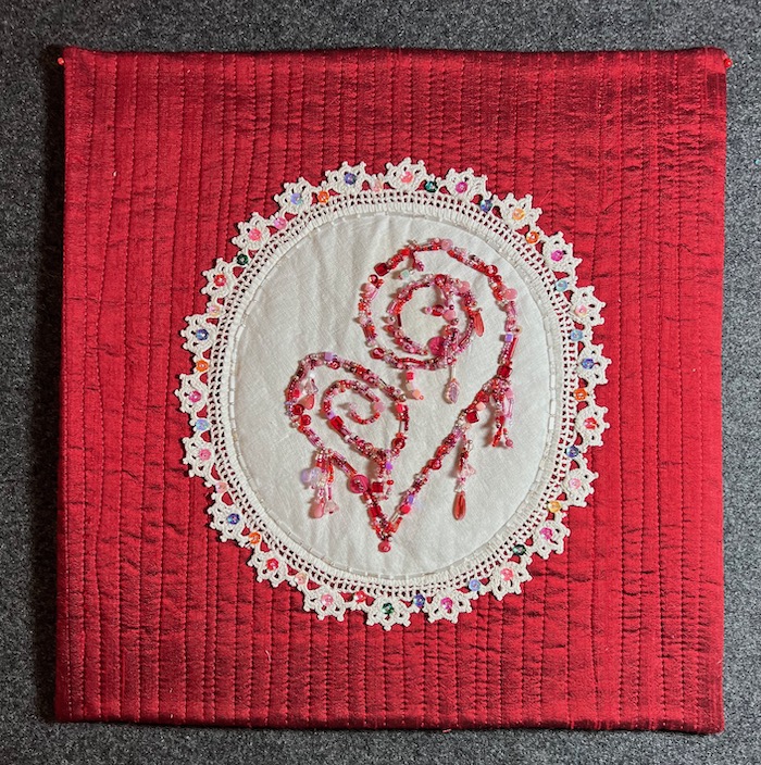 Fancy applique with beaded heart on red background, small art piece